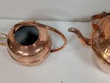 two copper pots on a white surface