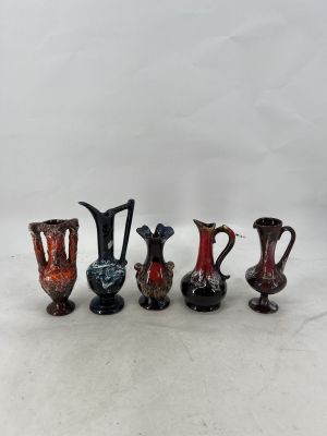 five different colored vases are lined up on a white surface