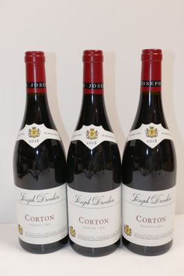 trois bouteilles de vin rouge sont alignées sur une table