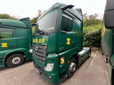 two green trucks parked next to each other in a parking lot