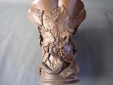 a brown vase with a bird on it on a table