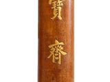 a tall wooden vase with gold writing on it