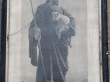 painting of a man holding a sheep in a frame on a brick wall