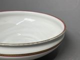 a white bowl with a gold rim on a table