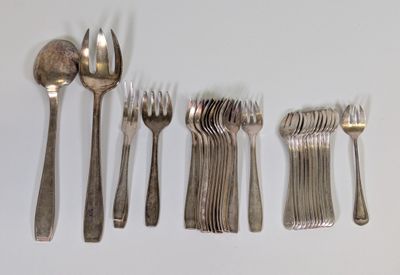 Plusieurs fourchettes et cuillères sont disposées en rangée sur une surface blanche