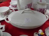 a red table with a red table cloth and white dishes and cups and saucers on it