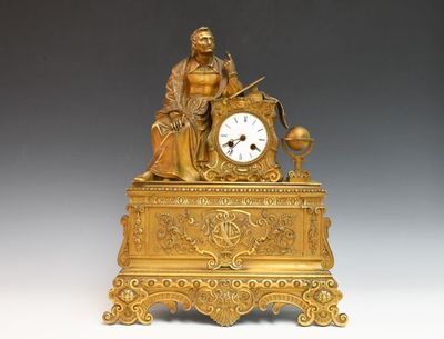 une horloge en or surmontée d'une statue représentant un homme assis