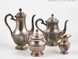 five silver teapots and two cups on a table