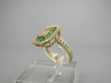 un gros plan d'une bague sertie d'un diamant vert et blanc, posée sur un socle transparent
