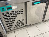 a stainless steel counter with two freezers and a person standing in front of it