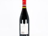 the bottle of red wine is sitting on a white surface