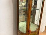 une vitrine avec une porte en verre, placée dans un coin