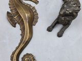 brass seahorse and lion figurines on a white surface
