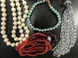 many different necklaces and bracelets on a black surface