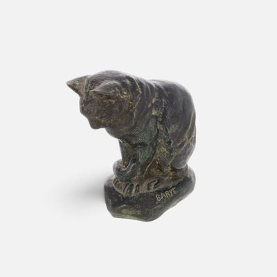statue of a cat sitting on a rock on a white surface