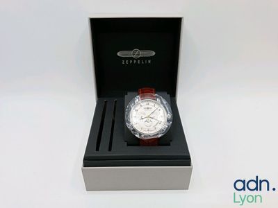 a close up of a watch in a box on a white surface
