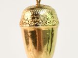 gold acorn ornament hanging from a chain on a white background