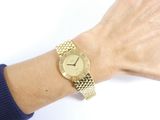 wrist shot of a woman wearing a gold watch on her wrist