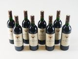 six bottles of wine are lined up in a row on a white surface