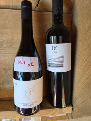 deux bouteilles de vin posées sur une étagère l'une à côté de l'autre