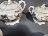 two teapots and two cups sitting on a table