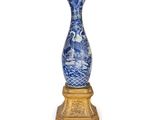 un vase bleu et blanc posé sur un socle doré