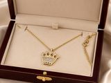a gold necklace with a crown on it in a box