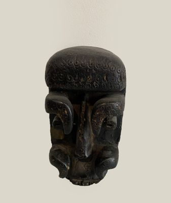 a black sculpture of a man ' s face on a white wall