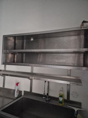 a kitchen with a sink and a metal shelf above it