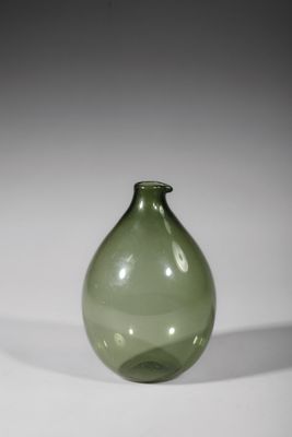 a green glass vase sitting on a white surface