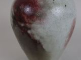 a white and red vase sitting on a white surface
