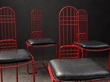 trois chaises en métal rouge avec des assises en cuir noir dans une pièce sombre