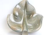a close up of a leaf shaped dish on a white surface