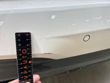 a person that is holding a ruler in front of a car