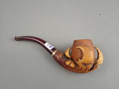 une pipe posée sur une table, sur laquelle est posé un chapeau