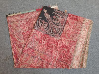 two pieces of red and black paisley fabric on a gray surface
