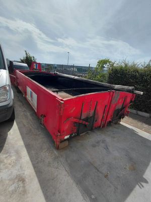 a red dumpster sitting in a parking lot next to a white van