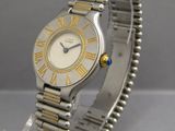une photo d'une montre-bracelet argentée et dorée posée sur un socle transparent