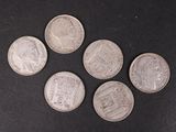 six pièces d'argent sont disposées en cercle sur une surface noire