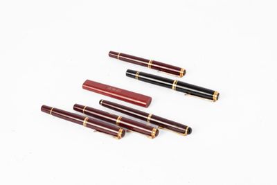 quatre stylos sont alignés sur une surface blanche
