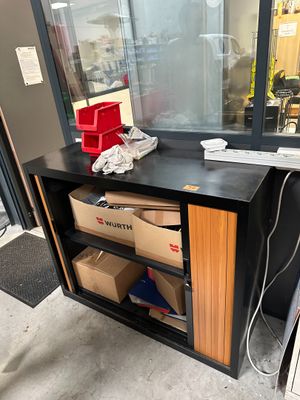a desk with a phone and boxes in front of a window