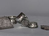 plusieurs objets en argent posés sur une table, à côté d'un livre et d'autres objets
