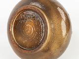 a brown vase that is sitting on a white surface