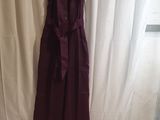 a dress hanging on a hanger in front of a curtain