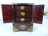 a small wooden chest with three drawers and a door open