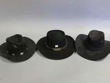 three black hats are lined up on a white surface