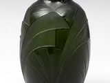un vase vert posé sur une surface blanche