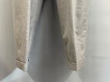 un pantalon beige suspendu à un cintre devant un mur blanc