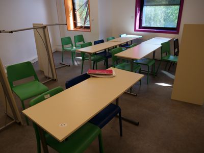 tables and chairs in a room with a window and a book on the table