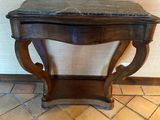 a small wooden table with a marble top on a tiled floor